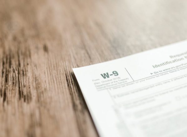 A close-up of a W-9 tax form placed on a wooden desk, emphasizing paperwork and finance.