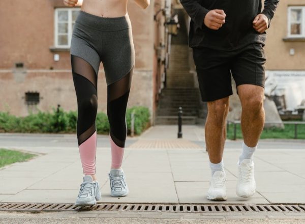 Two adults jogging outdoors, promoting health and fitness in an urban setting.