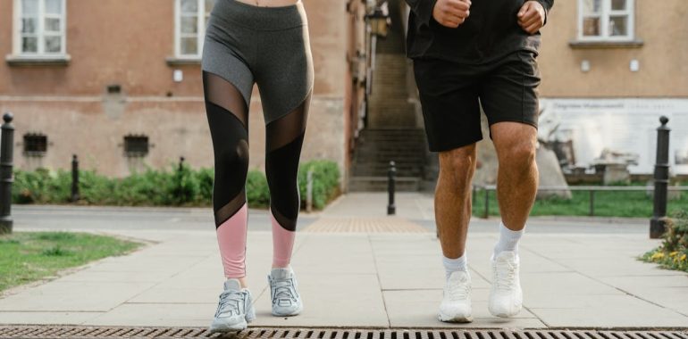 Two adults jogging outdoors, promoting health and fitness in an urban setting.
