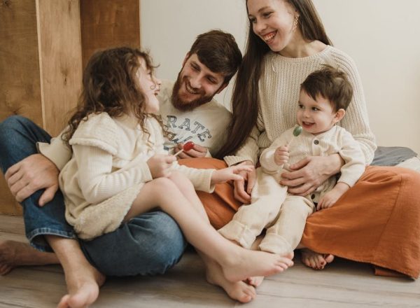 Smiling family of four sitting on the living room floor, enjoying quality time together.