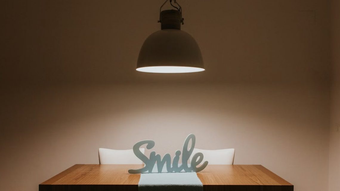Stylish interior featuring a wooden table, modern lamp, and 'Smile' decor for a warm ambiance.