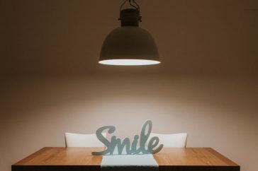 Stylish interior featuring a wooden table, modern lamp, and 'Smile' decor for a warm ambiance.