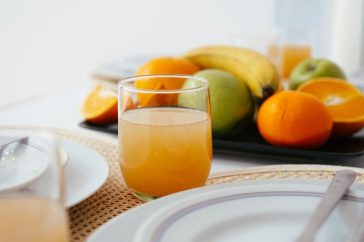 Bright and fresh breakfast setup featuring orange juice and a variety of fruits on a neatly arranged table.